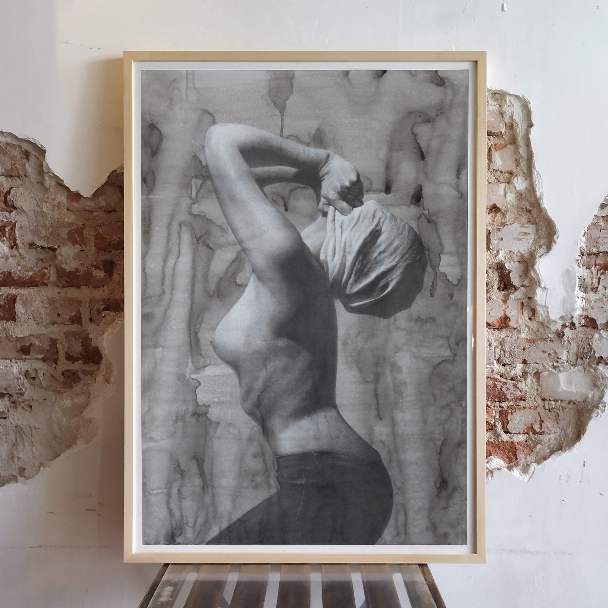 Obra La herencia de Eva II enmarcada sobre una pared de ladrillo